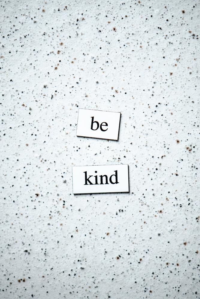 be kind written on a black and white speckled background