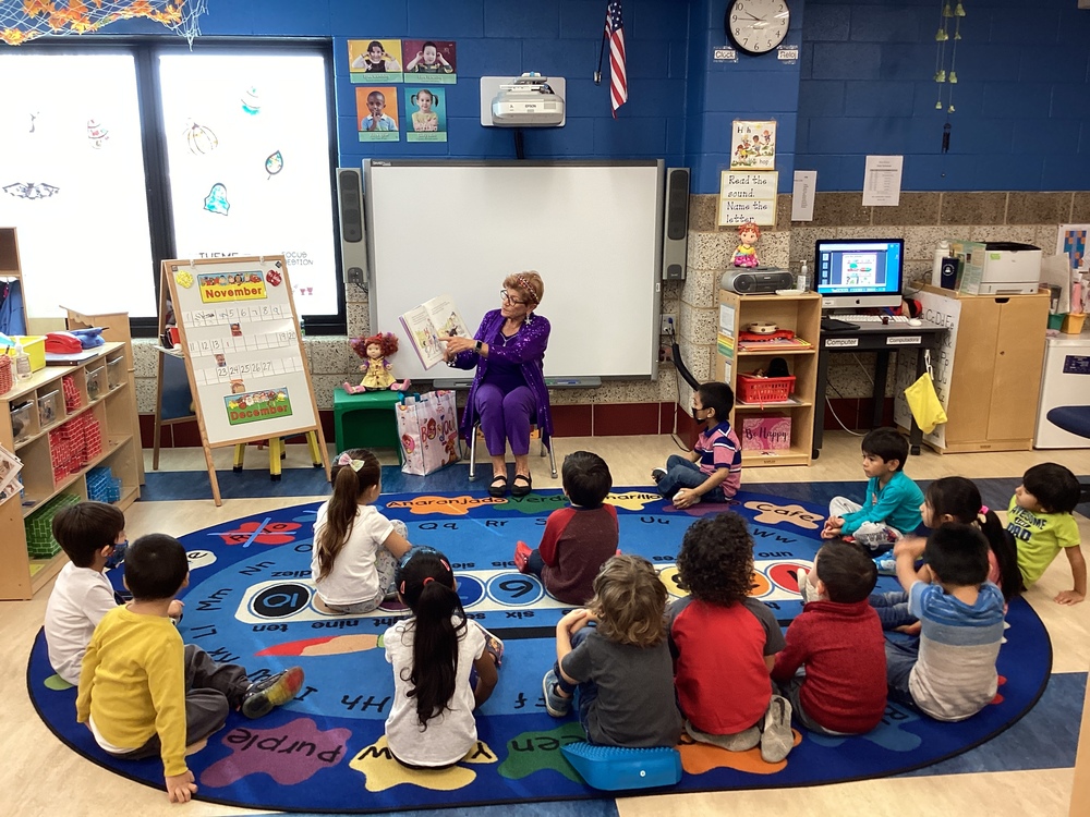 Ms. Nancy reading a fancy nancy book to group of students 