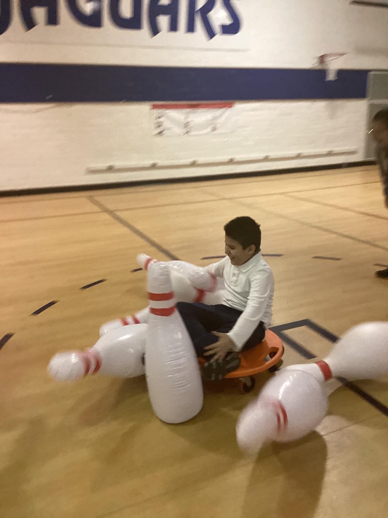 student sitting on scooter as it knocks down large pins