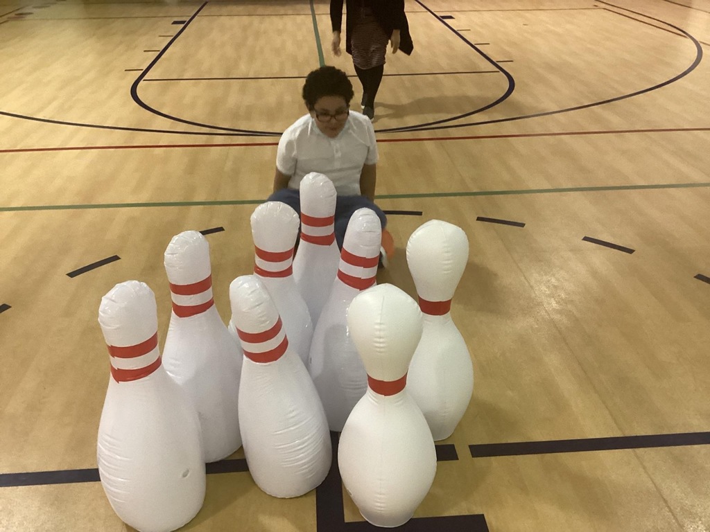 student sitting on scooter in front of large bowling pins