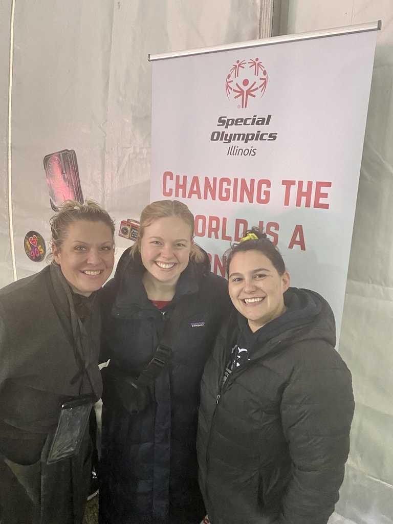 3 staff posing in front of special olympics banner